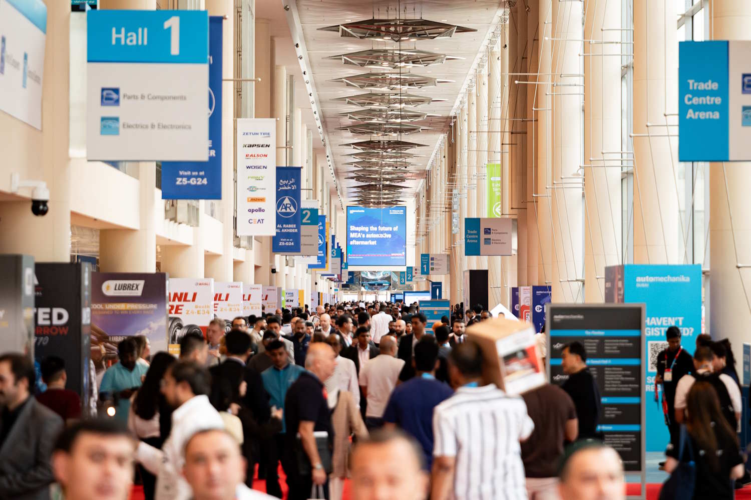 Automechanika Dubai 2025 show-floor concourse with visitors moving between exhibition halls.